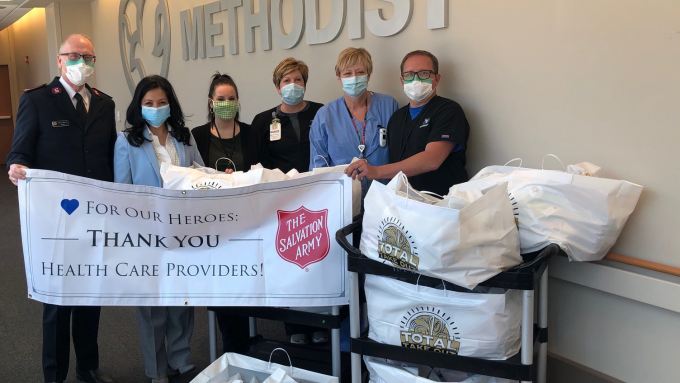 Methodist Hospital employees posing with donations in front of a Methodist sign