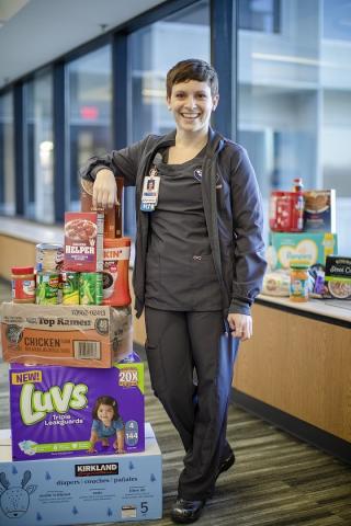 Photo of Amanda Harvey, BSN, RN, standing with food pantry donations